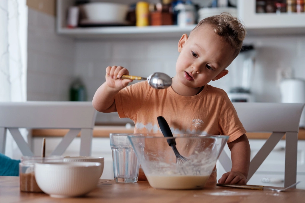 Chłopiec gotuje obiad, dziecko piecze ciasto