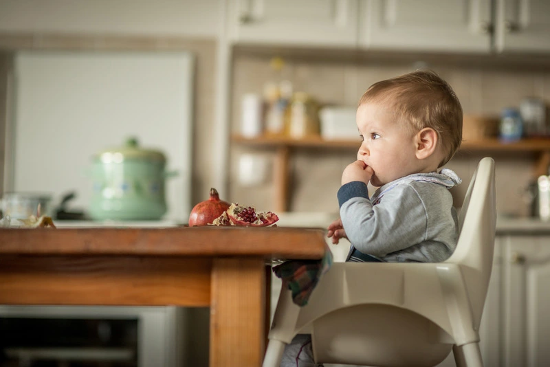 dziecko siedzi w krzesełku do karmienia przy stole