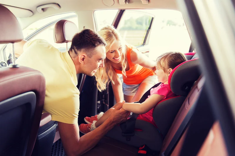Dziewczynka w foteliku samochodowym dla dziecka z rodzicami w aucie
