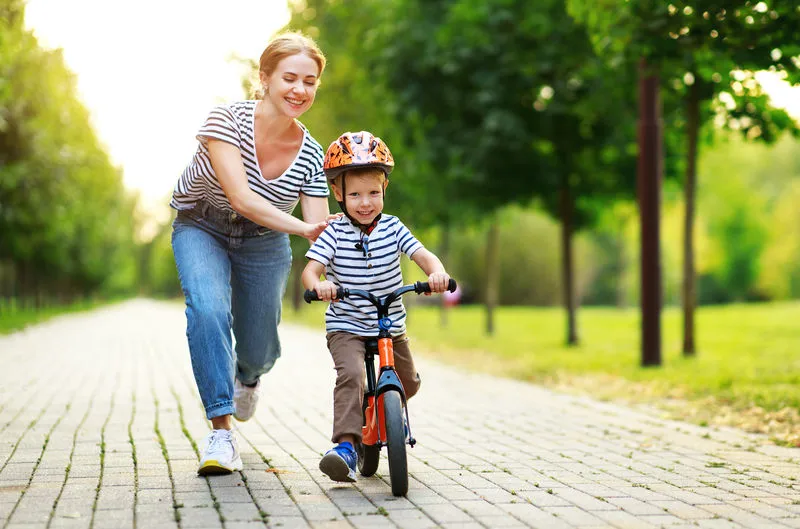 rowerek biegowy mama bawi się z dzieckiem w parku
