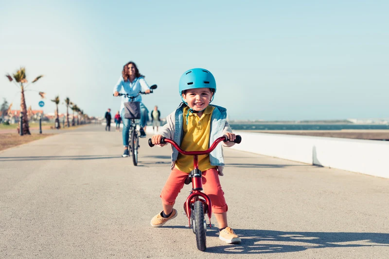 Rowerek biegowy - szczęśliwe dziecko z mamą w tle