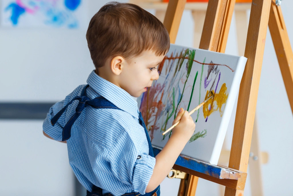 Chłopiec maluje obraz na płótnie